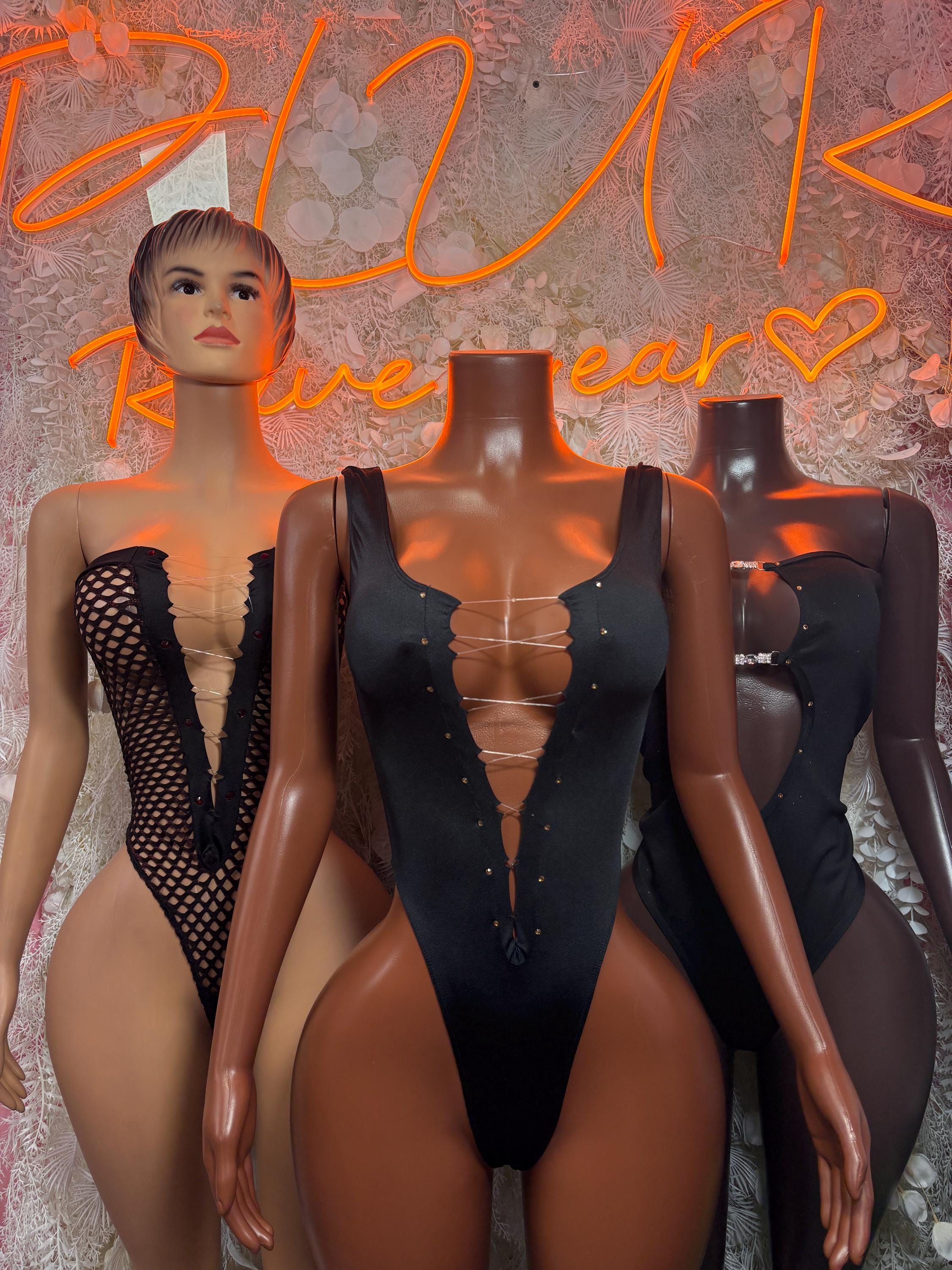 Black one-piece bodysuit with long sleeves, deep V front, and lace-up corset design