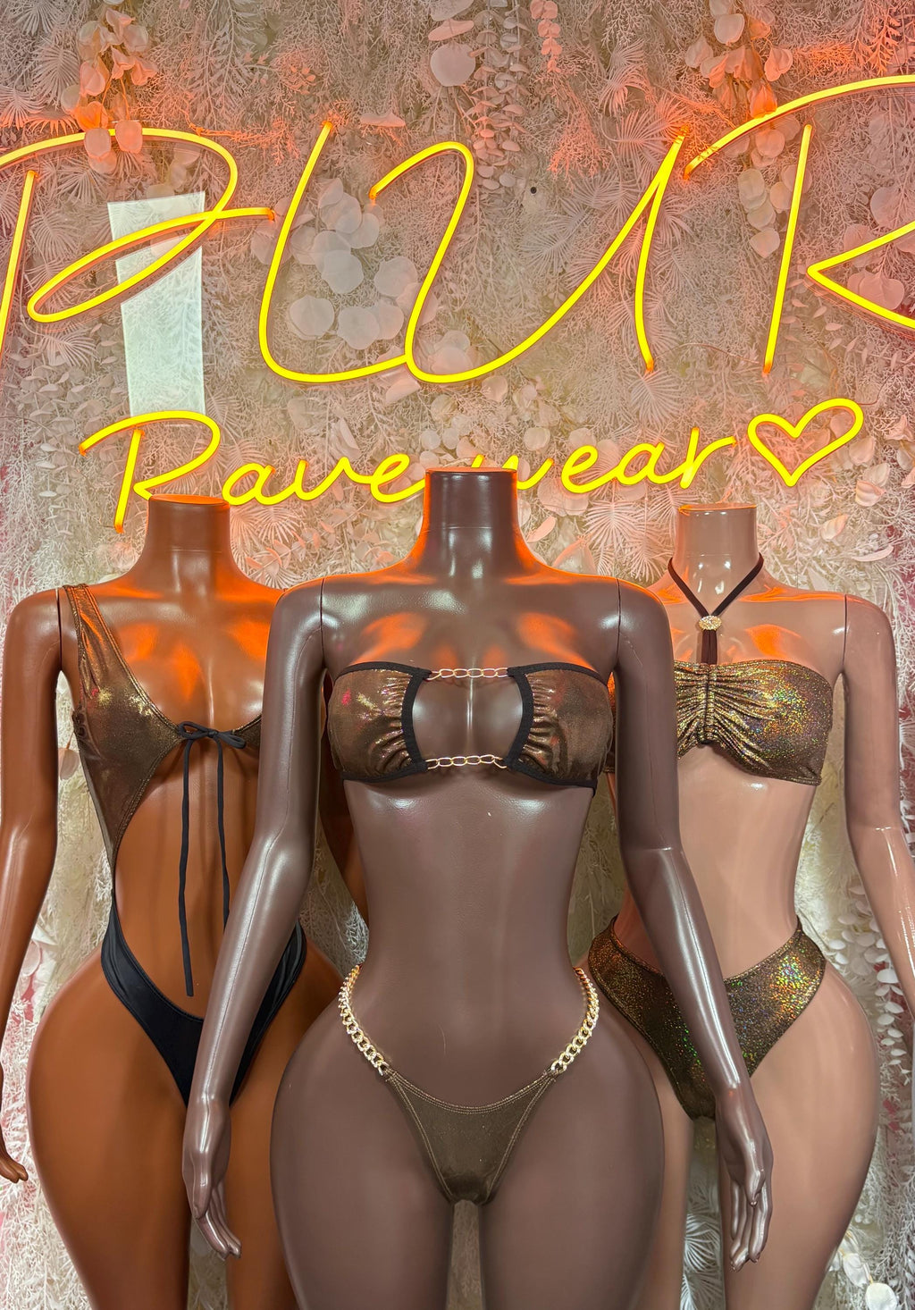 Three metallic chain bikini sets on mannequins: central dark, side gold and dark styles.