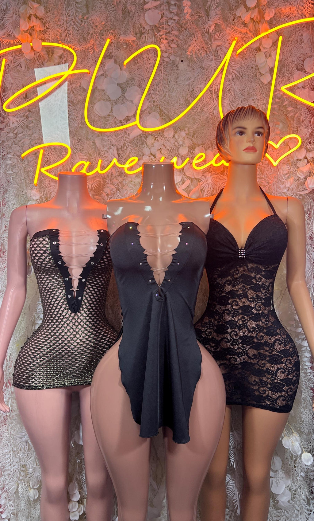 Black mesh mini dresses on three mannequins, including fishnet corset and lace babydoll dress