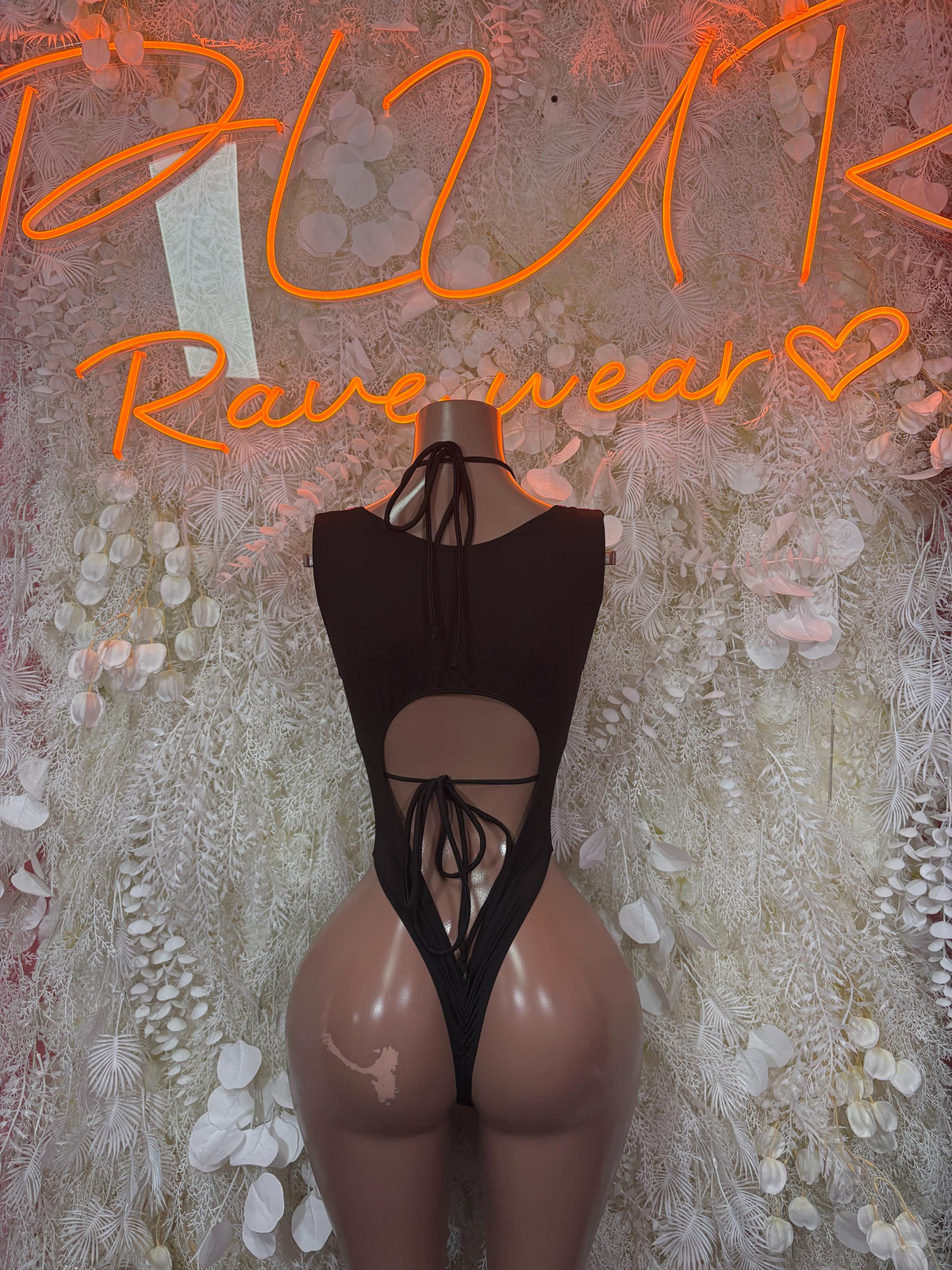 Black open-back one-piece bodysuit with lace-up detail and halter strap