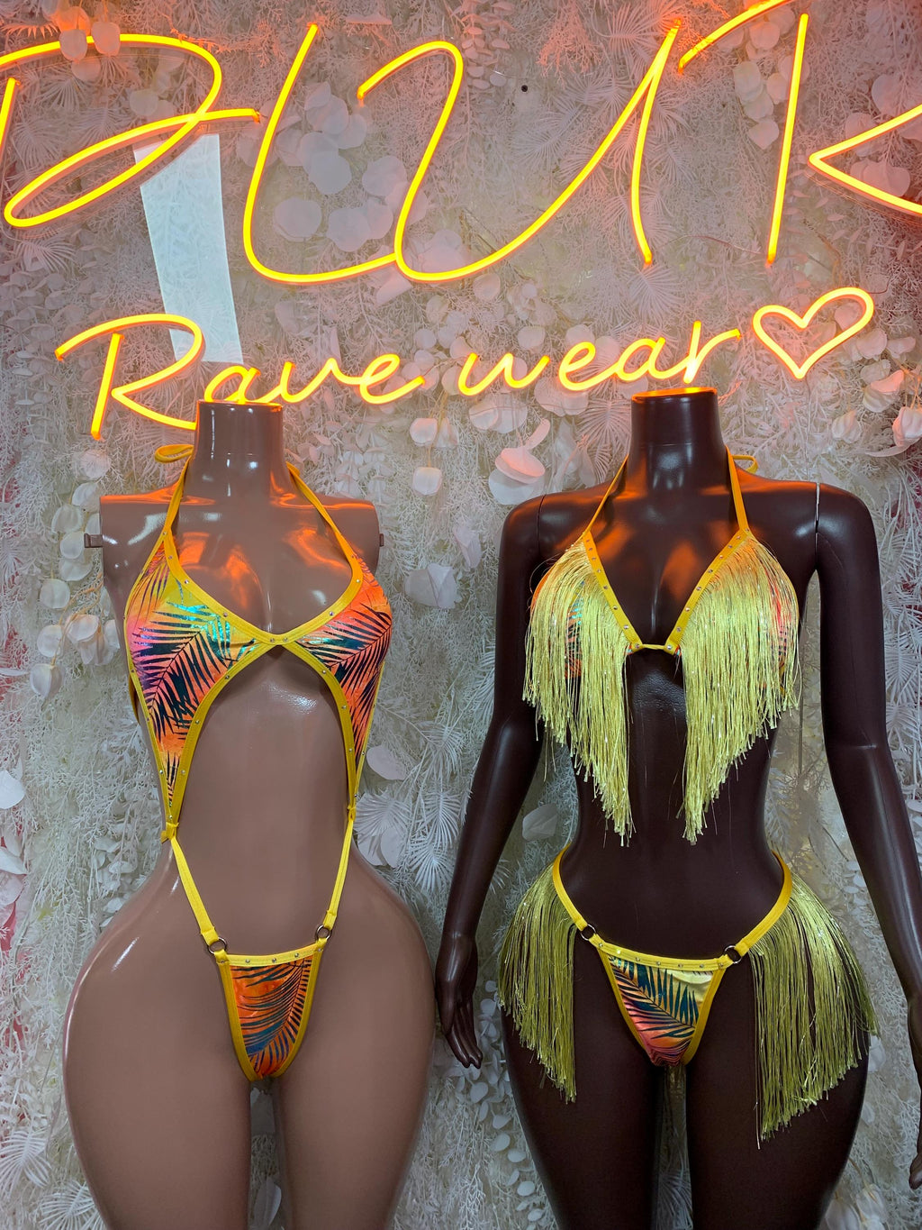 Metallic tropical-print bodysuits on mannequins, yellow-trim halter with fringed chest