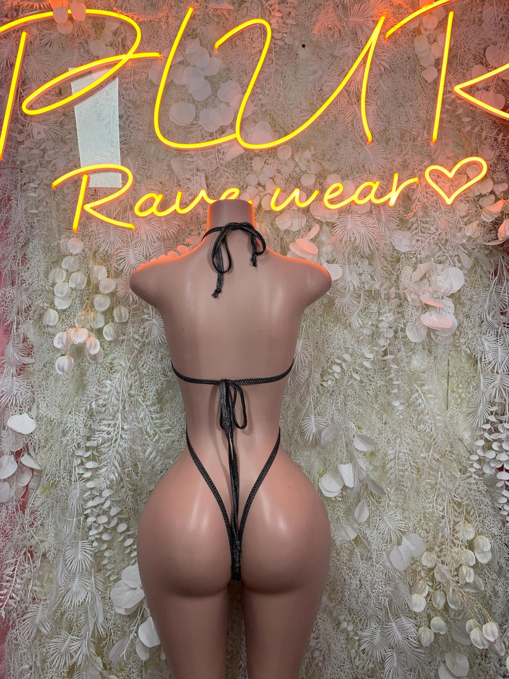 Matte black latex slingshot bodysuit with crisscross tie-back and thong back