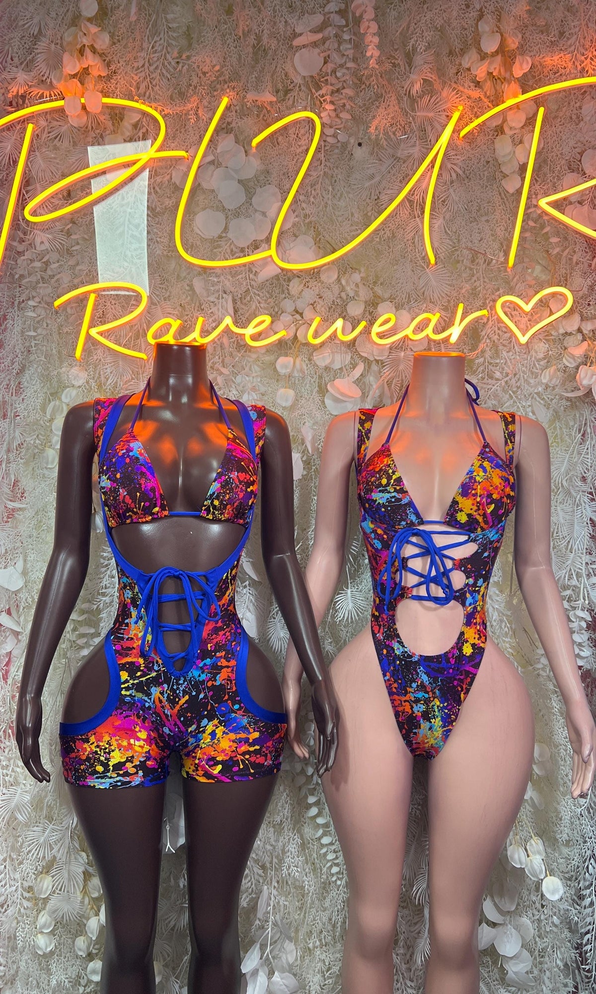 Paint-splatter rave bodysuits on two mannequins with blue lace-up details
