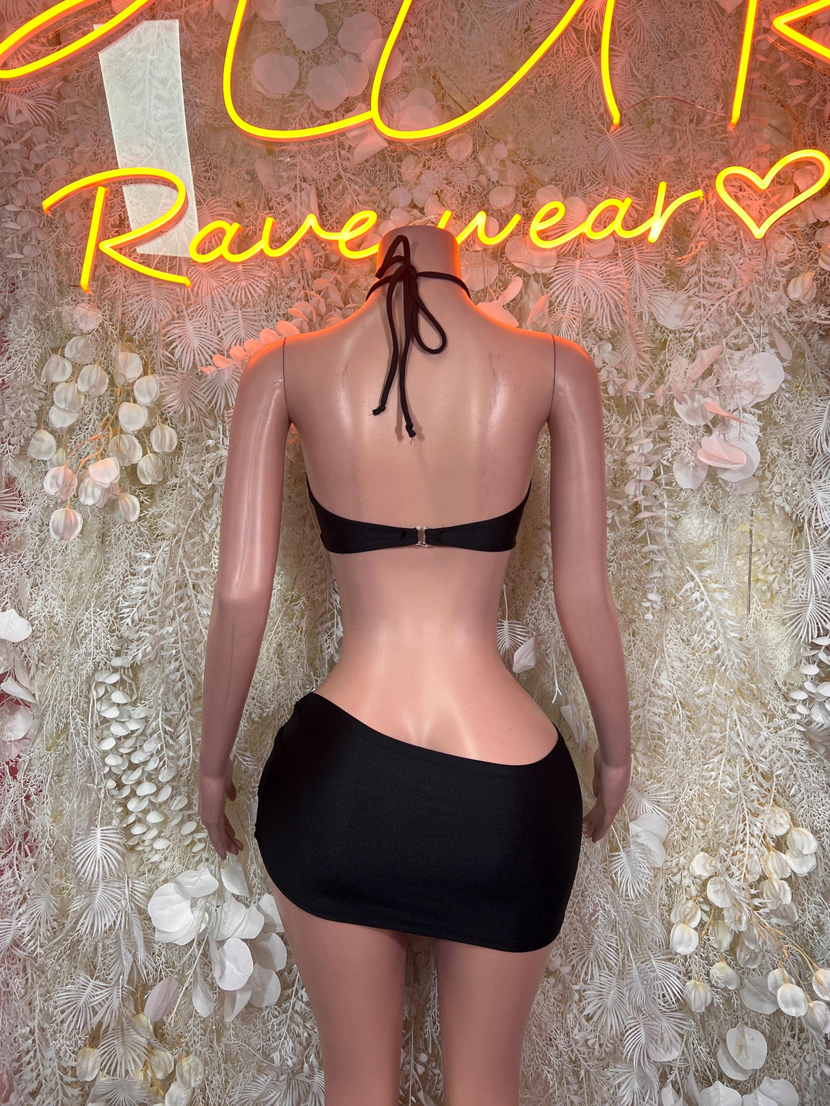 Black halter crop top with back tie and crisscross straps, matching mini skirt, back view