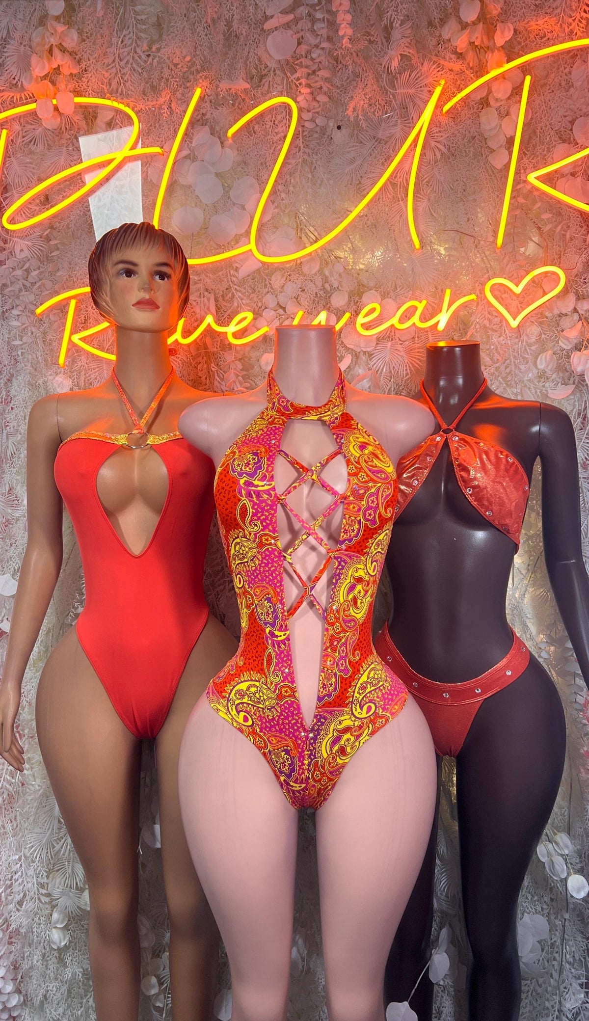 Bottlegirl orange one-piece bodysuit on mannequin; gold-patterned bodysuit beside it