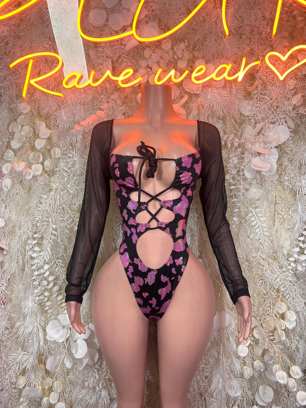 Pink cow print bodysuit with black sheer long sleeves and lace-up front cutouts
