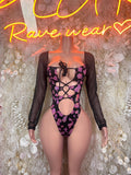 Pink cow print bodysuit with black sheer long sleeves and lace-up front cutouts