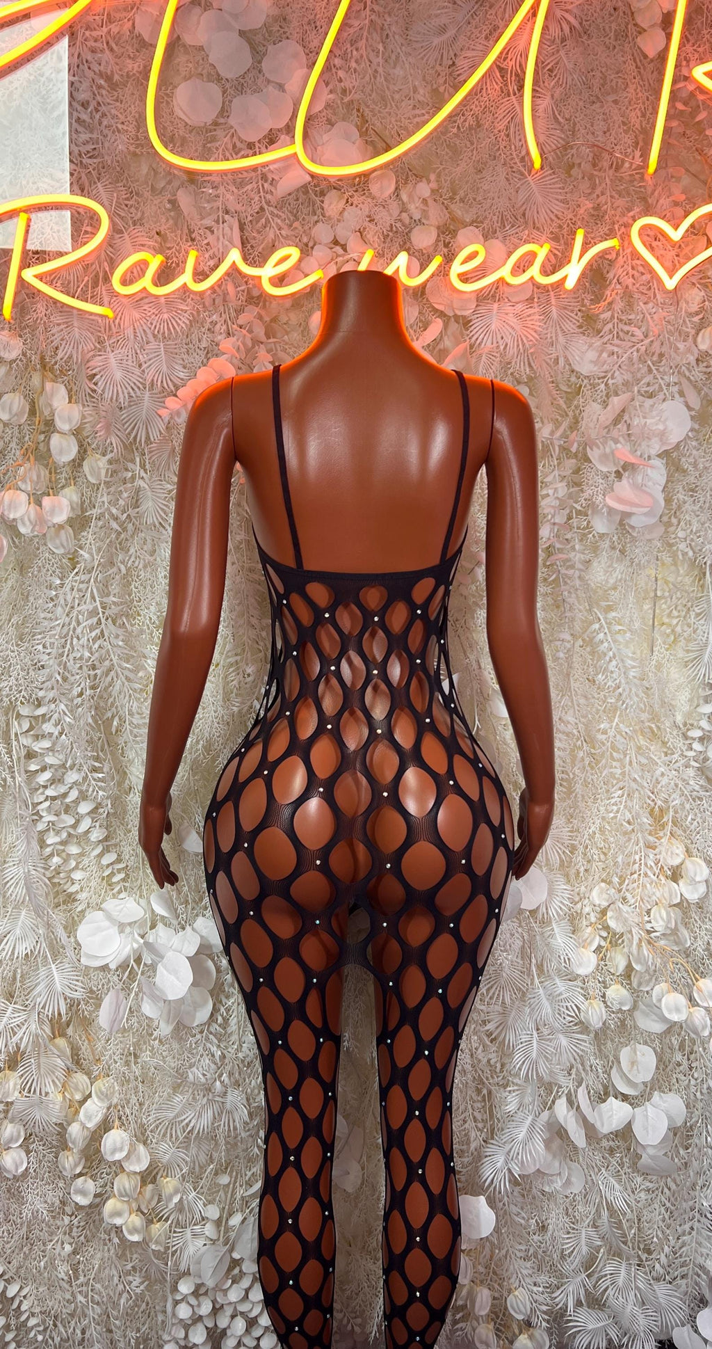 Black sheer fishnet backless bodysuit with thin straps on mannequin