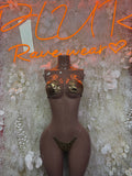 Black cutout bodysuit on a mannequin, gold metallic cups with shoulder fringe