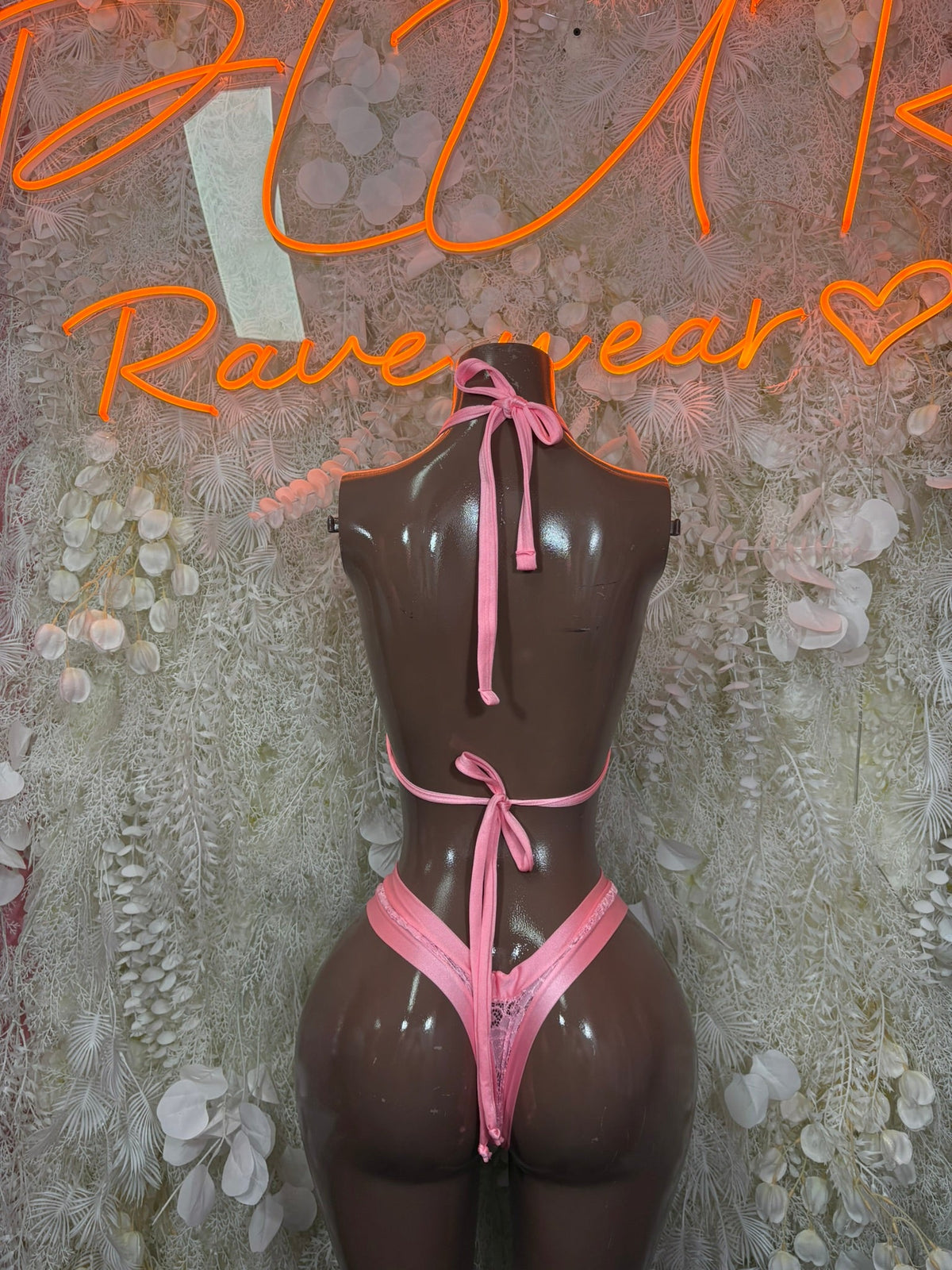 Pink lace triangle bikini set on mannequin with bow tie halter top and matching bottoms