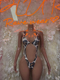 Cow print slingshot bodysuit with cutout front and thin straps, one-piece.