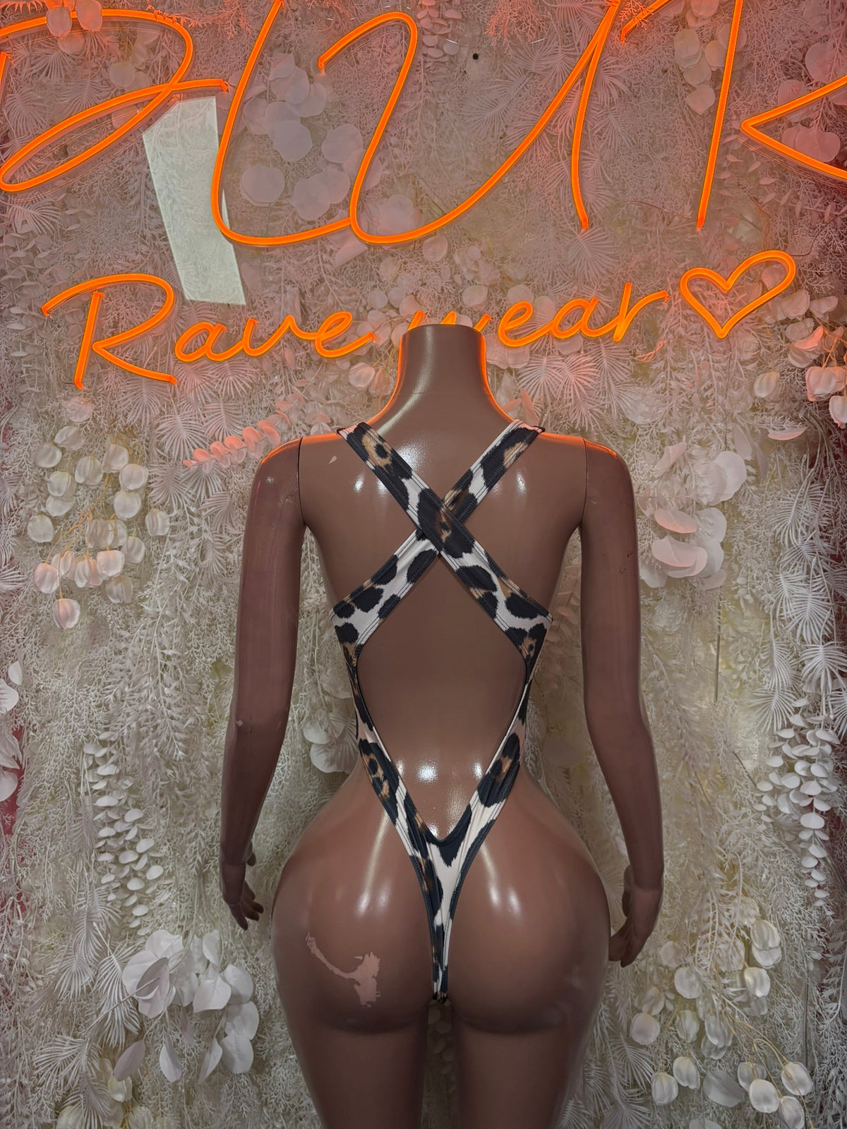Cow print backless slingshot bodysuit with crossed straps and high cut legs, one-piece.