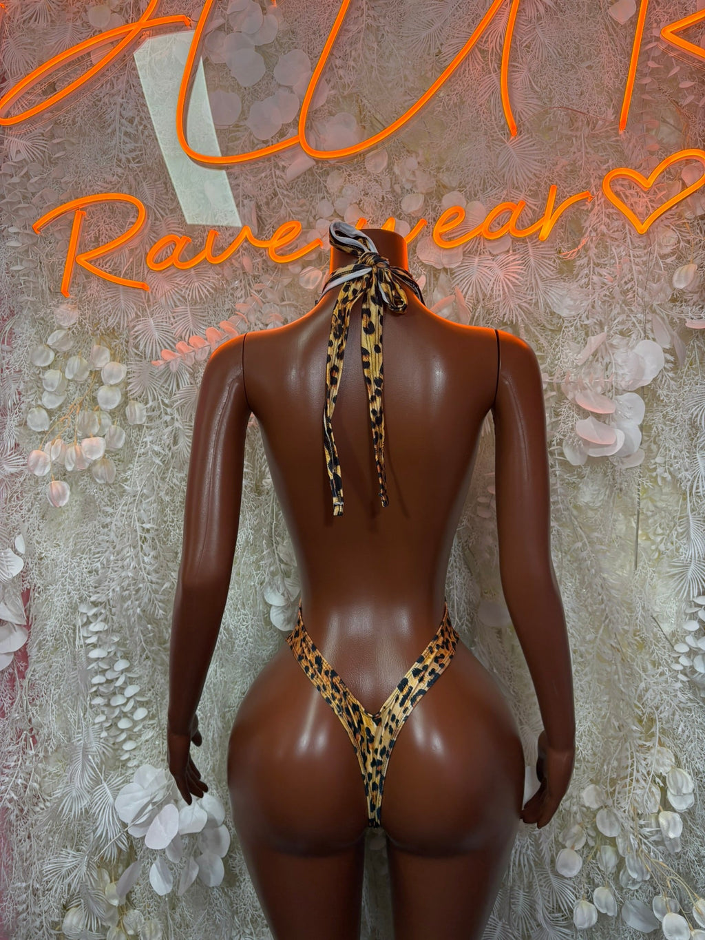 Gold leopard thong bodysuit with halter straps and tied back on mannequin
