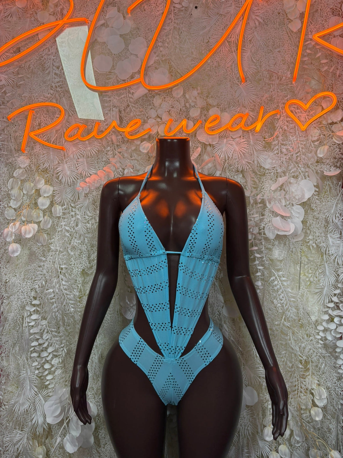 Light blue halter bodysuit with deep V neckline and perforated cutout details, on mannequin