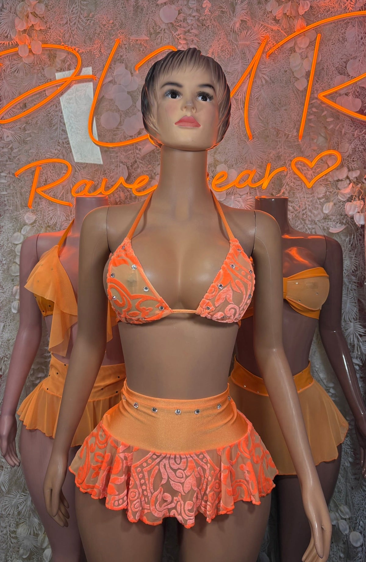 Peach sheer ruffle bikini set on mannequin, triangle bandeau top and flared mini skirt