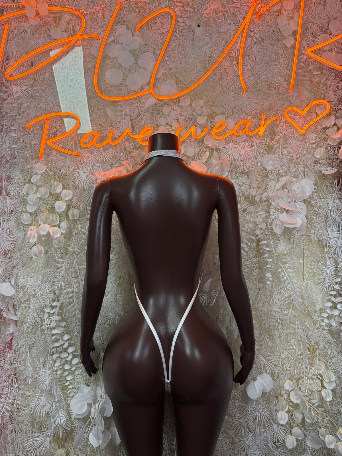 Back view of silver chain-detail plunging glitter bodysuit on mannequin
